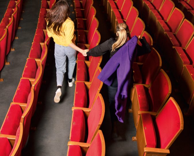 Zwei Frauen laufen durch den Zuschauerraum eines Theaters