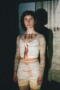 Foto mit Anna Klimovitskaya, vor der Leinwand stehend, die Projektion eines Standtages verschmilzt mit ihrem Körper