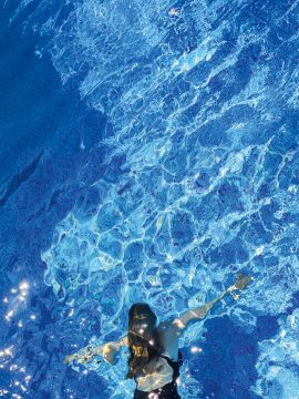 Foto Blick von oben in einen blauen Pool, tauchende Frau im schwarzen Badeanzug