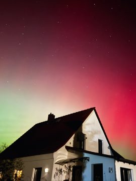 Foto mit weißem Haus in der Nacht, Himmel in rot und grün erhellt